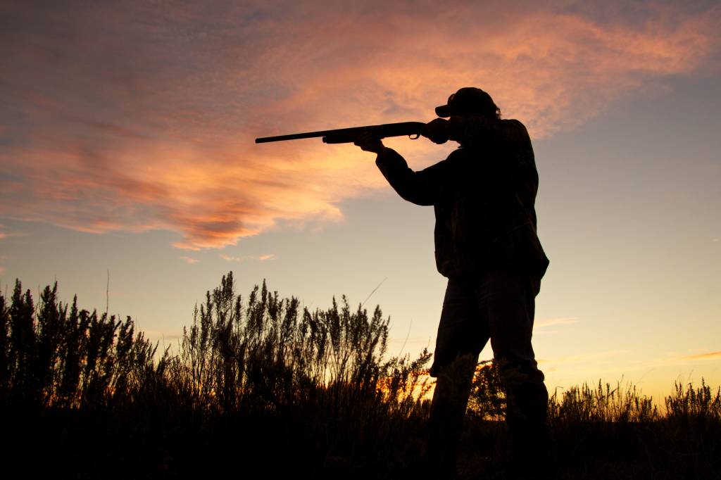 Hunter Silhouetted Shooting at Sunset