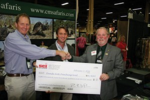 Presidente SCI Larry Higgins (derecha) entrega el cheque a Myles McCallum (izquierda) y Buzz Charlton (centro).